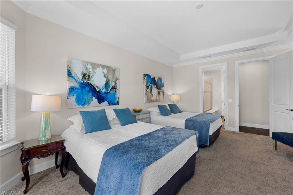 Bedroom featuring carpet flooring, crown molding, a raised ceiling, and ensuite bathroom