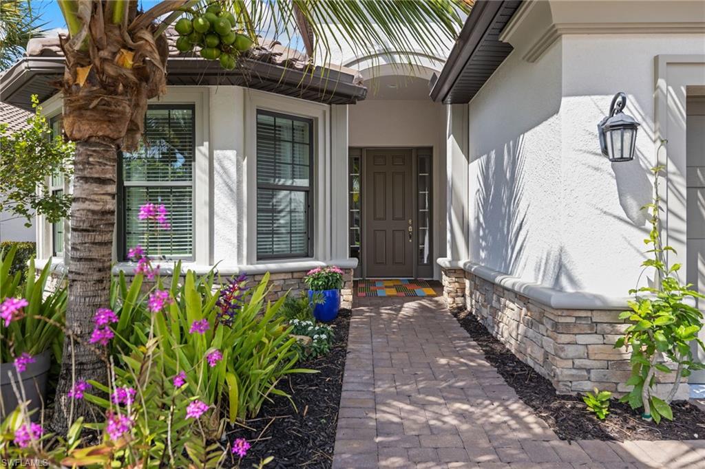 Doorway to property featuring stone siding and stucco siding