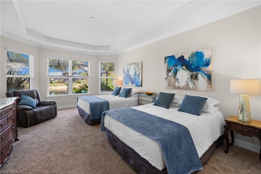 Carpeted bedroom with a tray ceiling and crown molding