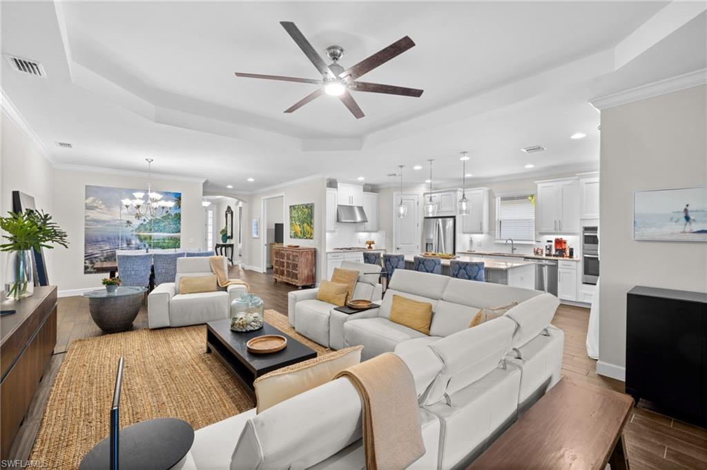 Living area with wood finish floors, arched walkways, ornamental molding, a ceiling fan, and a chandelier