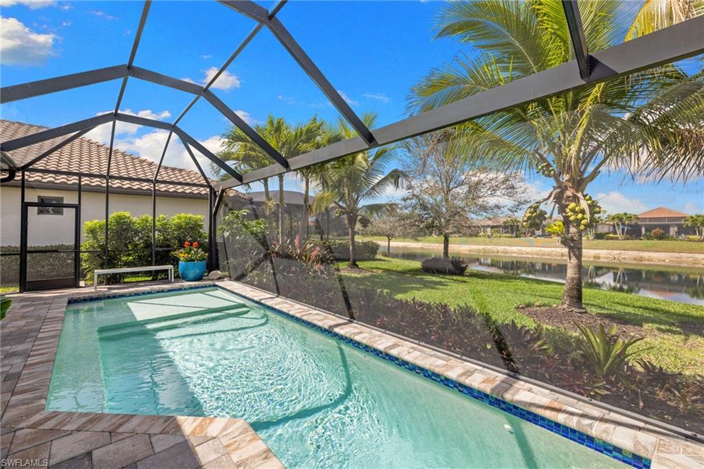 Swimming pool featuring a sunroom, a lanai, a lawn, and a water view