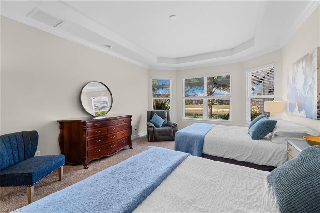 Carpeted bedroom with ornamental molding and a tray ceiling