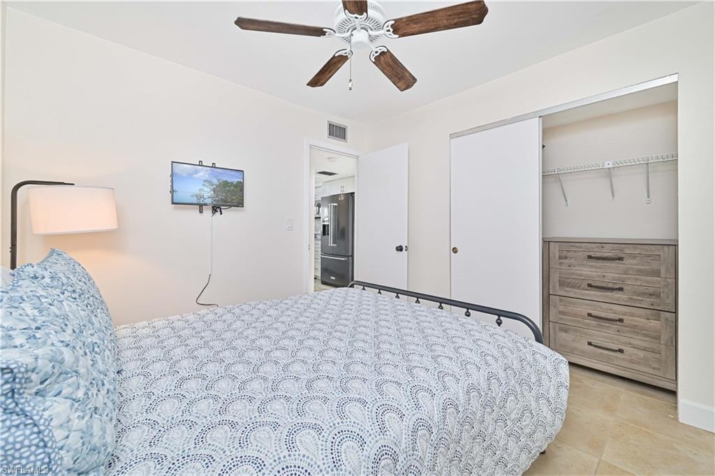 Bedroom featuring high end fridge, a closet, ceiling fan, and light tile patterned floors