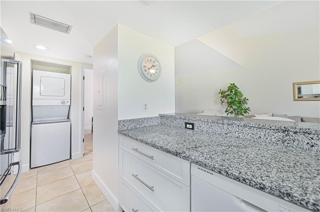 Bathroom with vanity, stacked washer / drying machine, light tile patterned floors, and recessed lighting