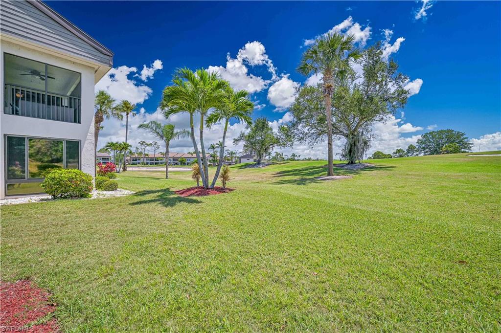 View of green lawn with a balcony and a ceiling fan