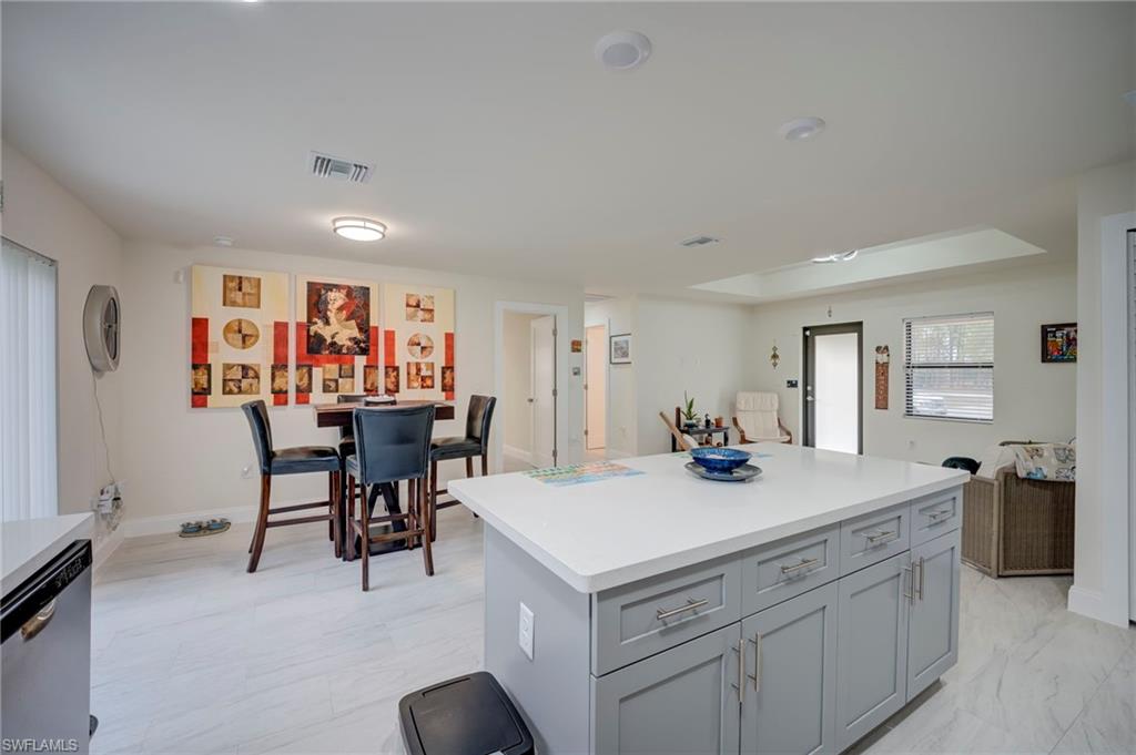 Kitchen with gray cabinetry, dishwasher, and a kitchen island