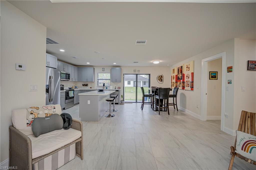 Kitchen featuring gray cabinets, a kitchen island, a kitchen bar, stainless steel appliances, and recessed lighting