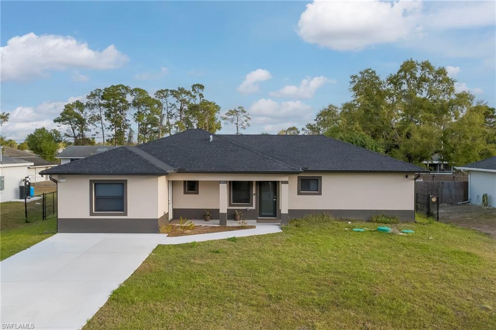 View of front facade with stucco siding, driveway, and a shingled roof