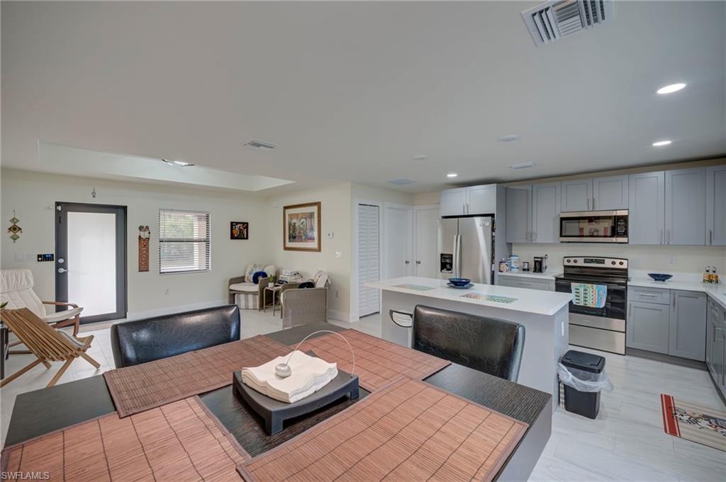 Kitchen featuring stainless steel appliances, gray cabinetry, a center island, open floor plan, and recessed lighting