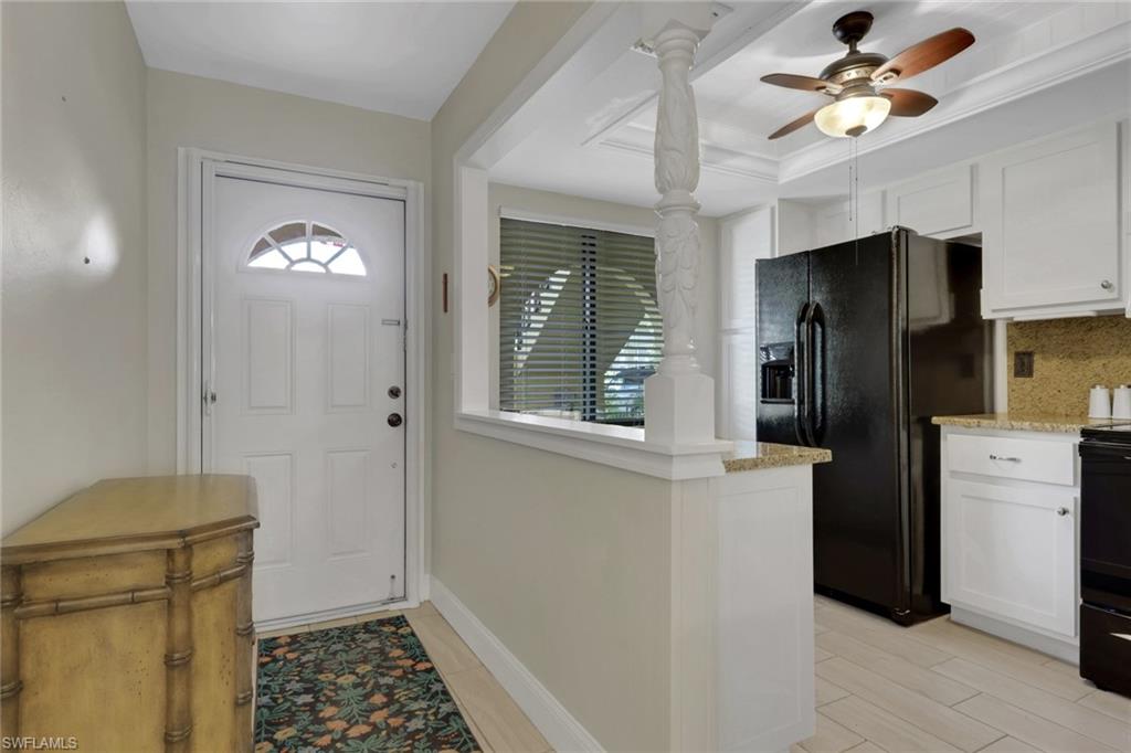 Foyer entrance with a ceiling fan, a raised ceiling, and light wood finished floors