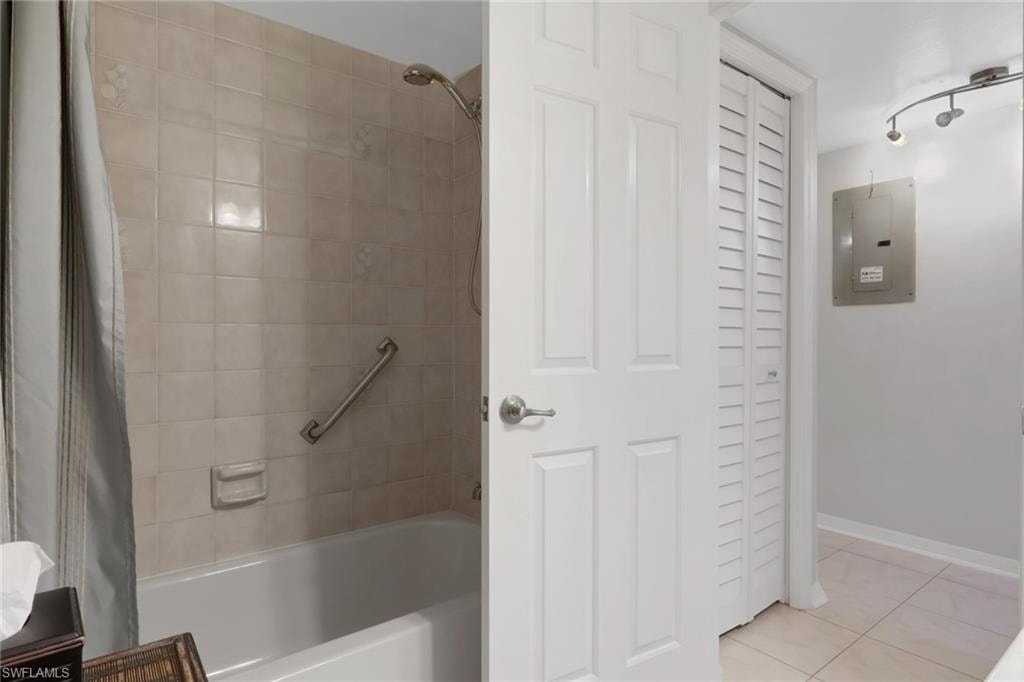 Full bathroom featuring a closet, shower / bath combo with shower curtain, electric panel, and light tile patterned flooring