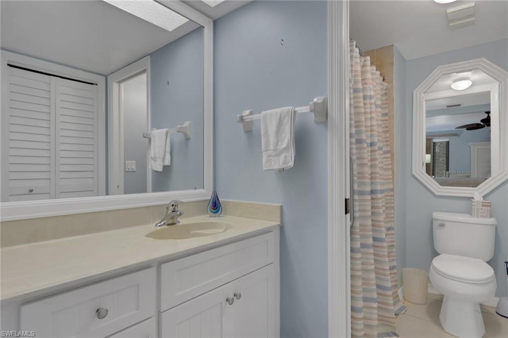 Full bathroom featuring vanity, a shower with shower curtain, a closet, a skylight, and light tile patterned floors