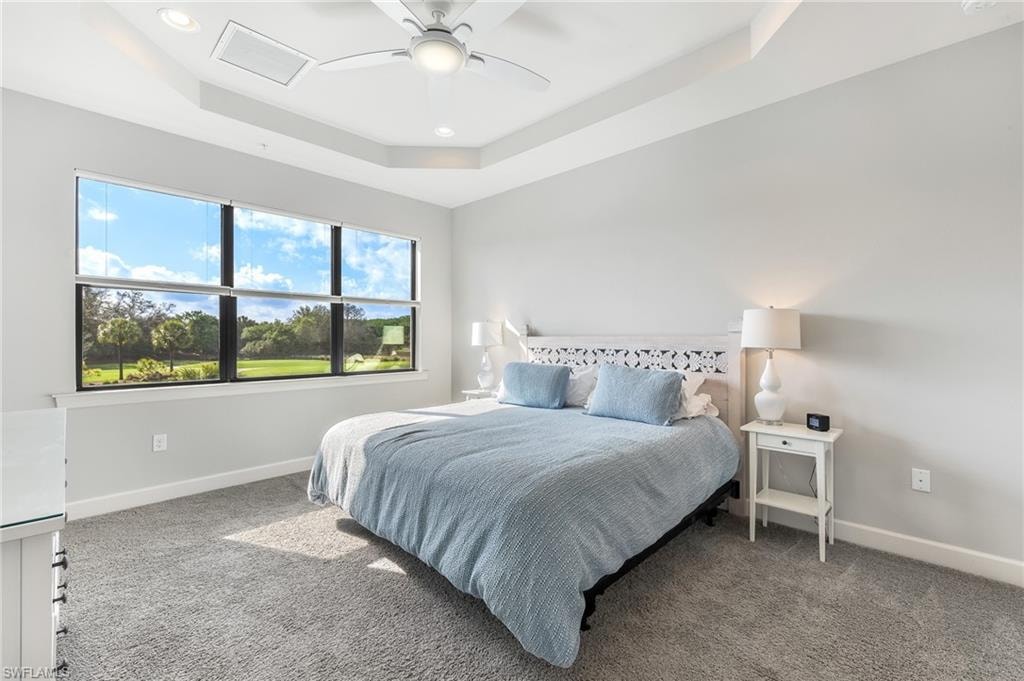Carpeted bedroom with a tray ceiling, recessed lighting, and ceiling fan