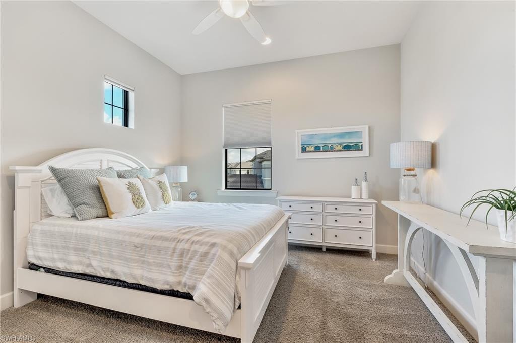 Bedroom featuring multiple windows, dark carpet, and a ceiling fan