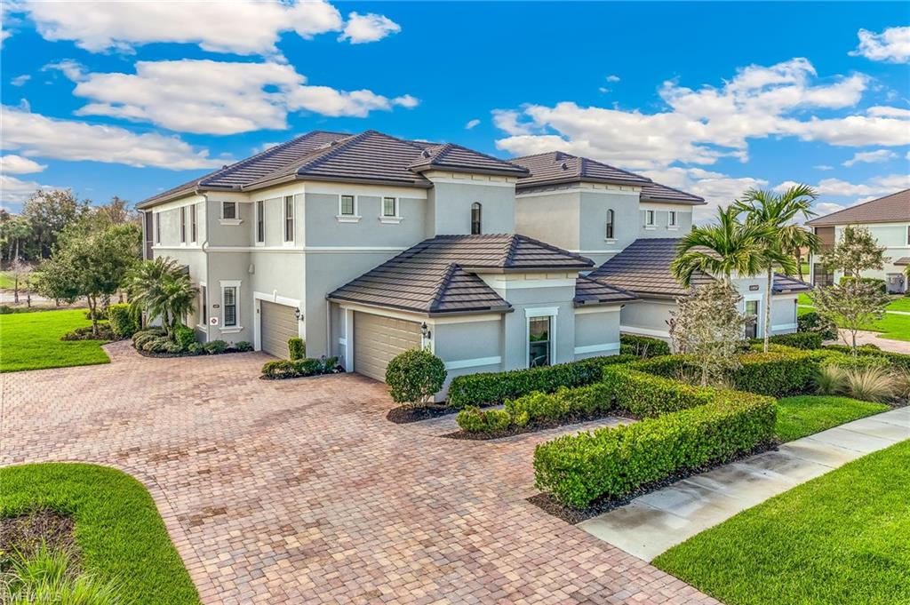 Mediterranean / spanish house featuring a front lawn, driveway, stucco siding, and a tiled roof