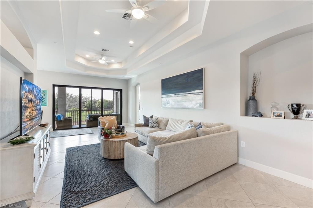 Living area with light tile patterned floors, a ceiling fan, recessed lighting, and a tray ceiling