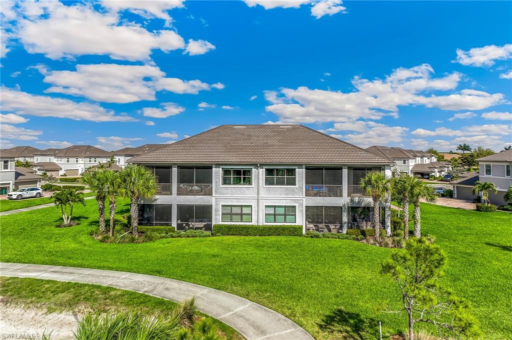 Back of property featuring a tiled roof, a residential view, a lawn, and a sunroom