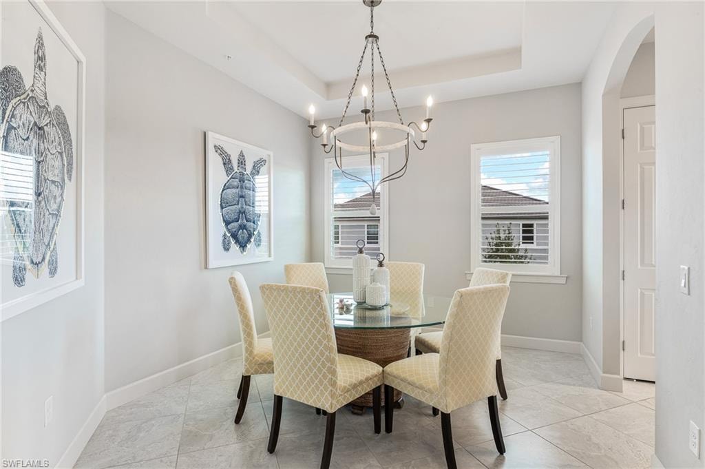 Dining space with arched walkways, hanging lights, and a raised ceiling