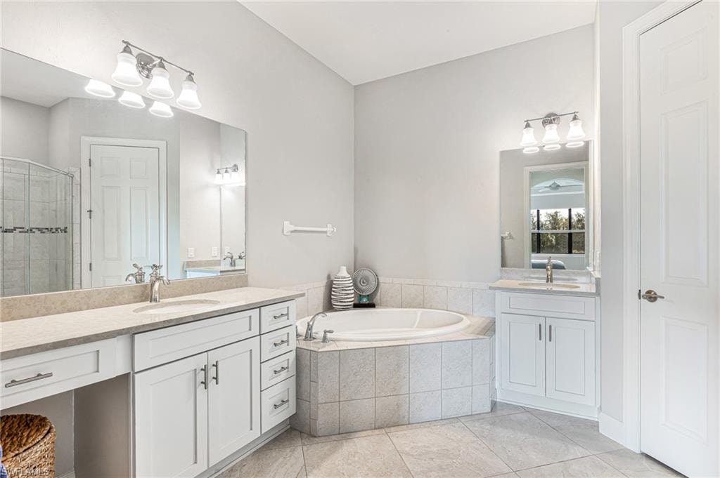 Bathroom with two vanities, a bath, and a shower stall