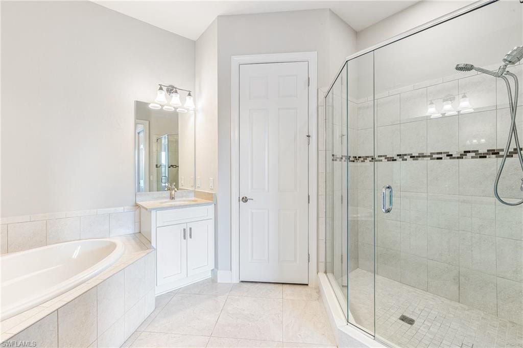 Full bathroom featuring a shower stall, vanity, a garden tub, and light tile patterned floors