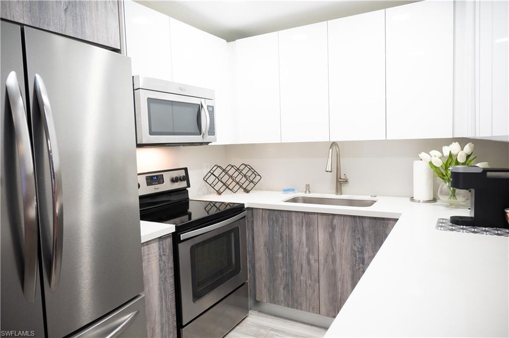 Kitchen featuring stainless steel appliances, two tone cabinets, and modern cabinets