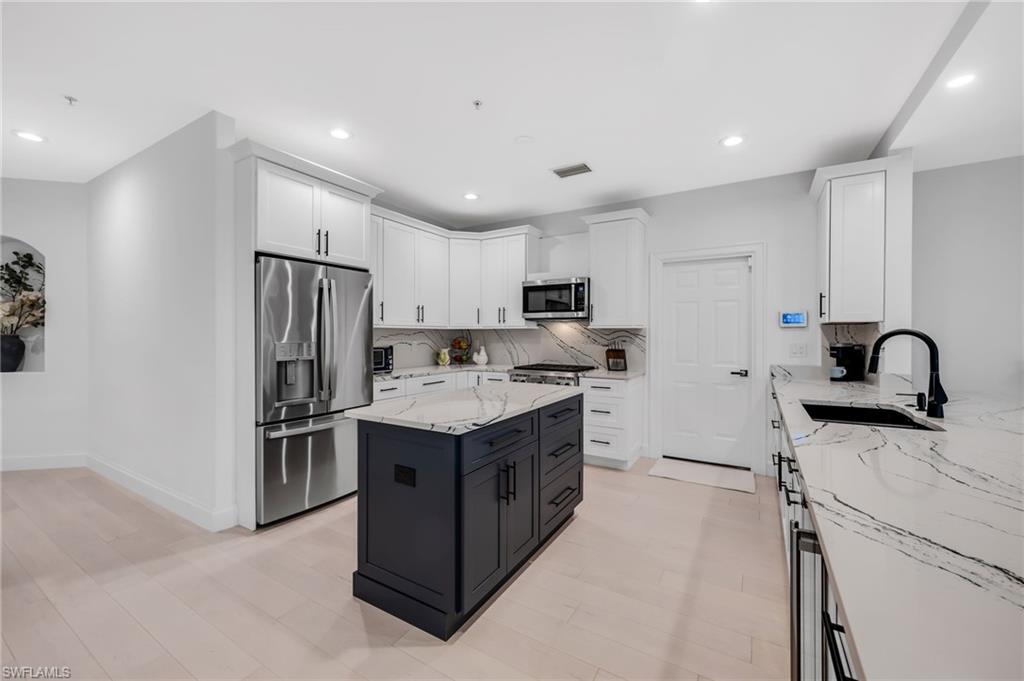 Bright kitchen with white cabinets stainless appliances