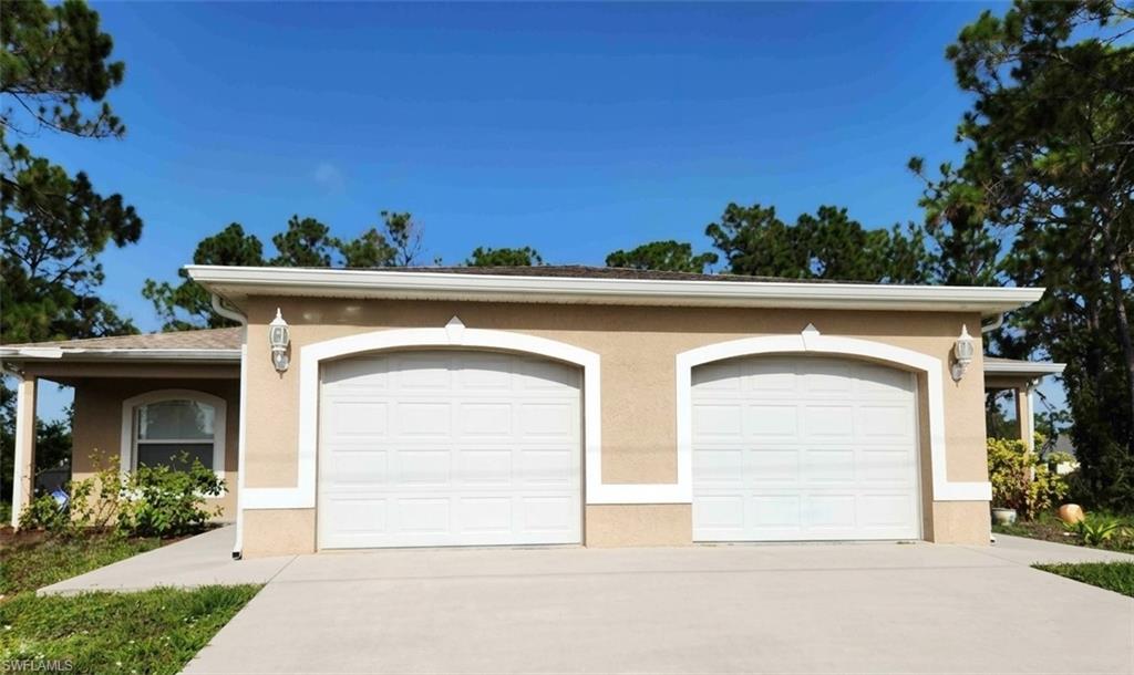 View of front of house with an attached garage, concrete driveway, and stucco siding