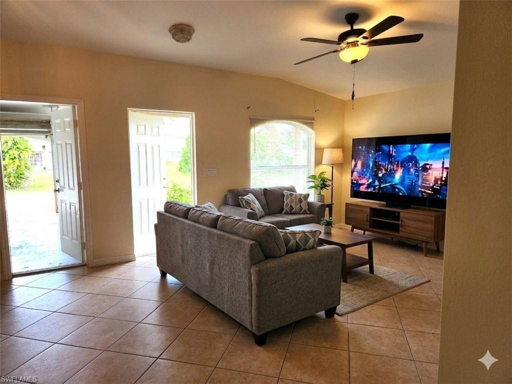 Living area featuring vaulted ceiling, a ceiling fan, and light tile patterned flooring