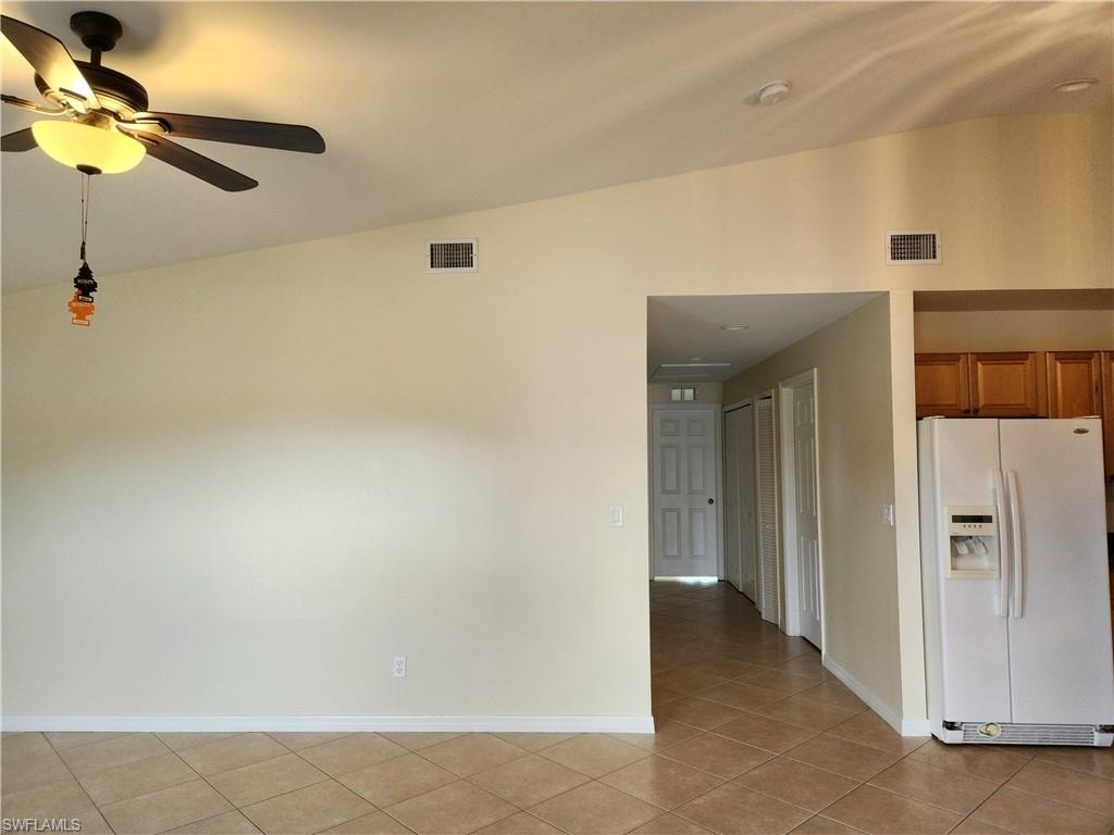 Spare room featuring a ceiling fan, vaulted ceiling, and light tile patterned flooring