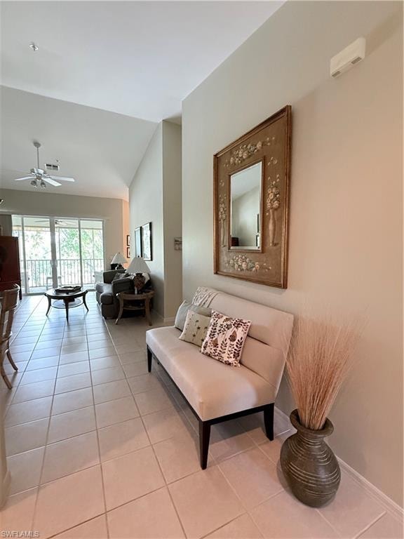 Living room featuring light tile patterned floors, vaulted ceiling, and ceiling fan