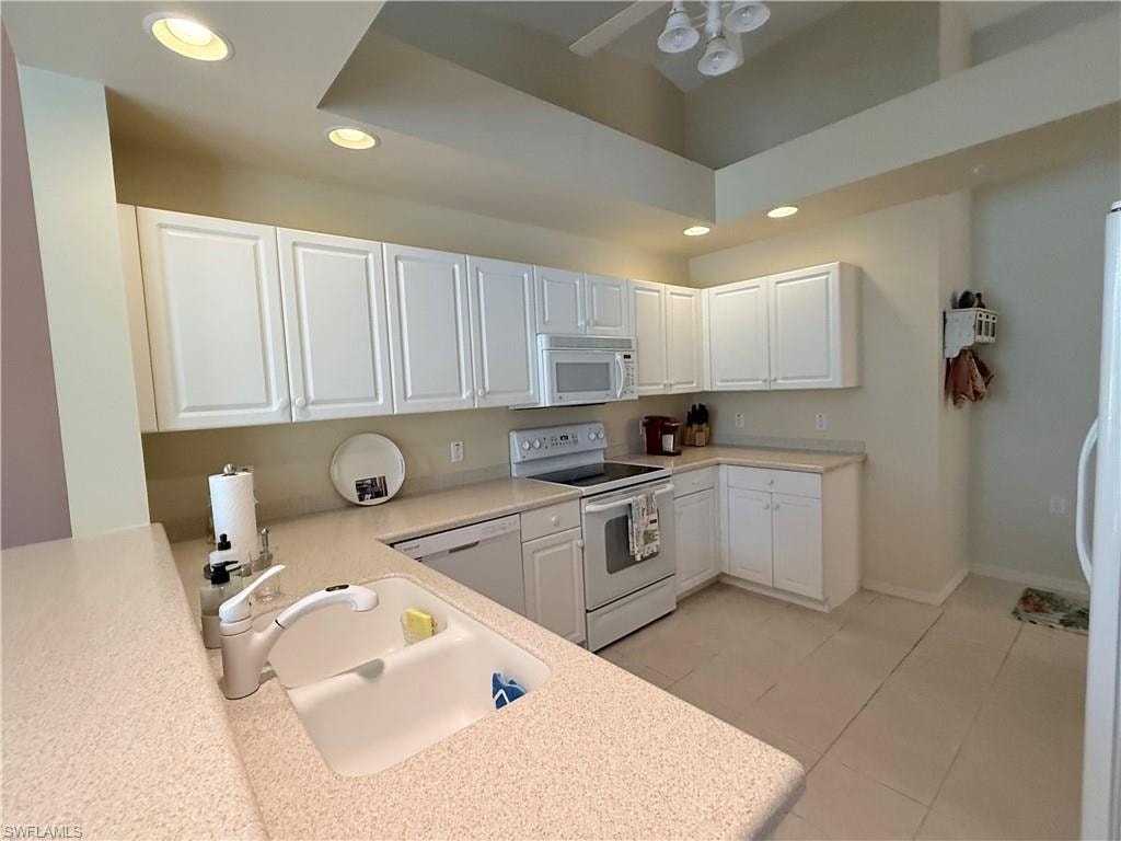 Kitchen featuring white cabinetry, recessed lighting, white appliances, light stone countertops, and light tile patterned flooring