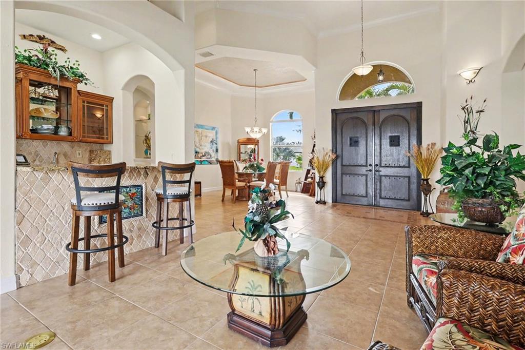 Foyer entrance with a high ceiling, light tile patterned floors, and arched walkways