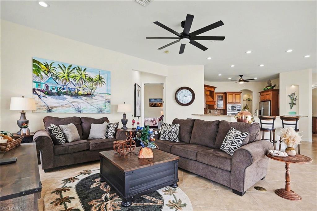 Living area with recessed lighting, a ceiling fan, arched walkways, and light tile patterned floors