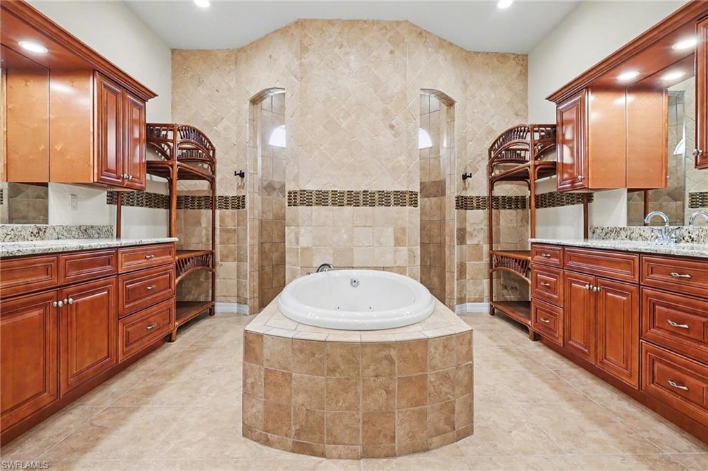 Full bath featuring walk in shower, two vanities, a jetted tub, tasteful backsplash, and recessed lighting