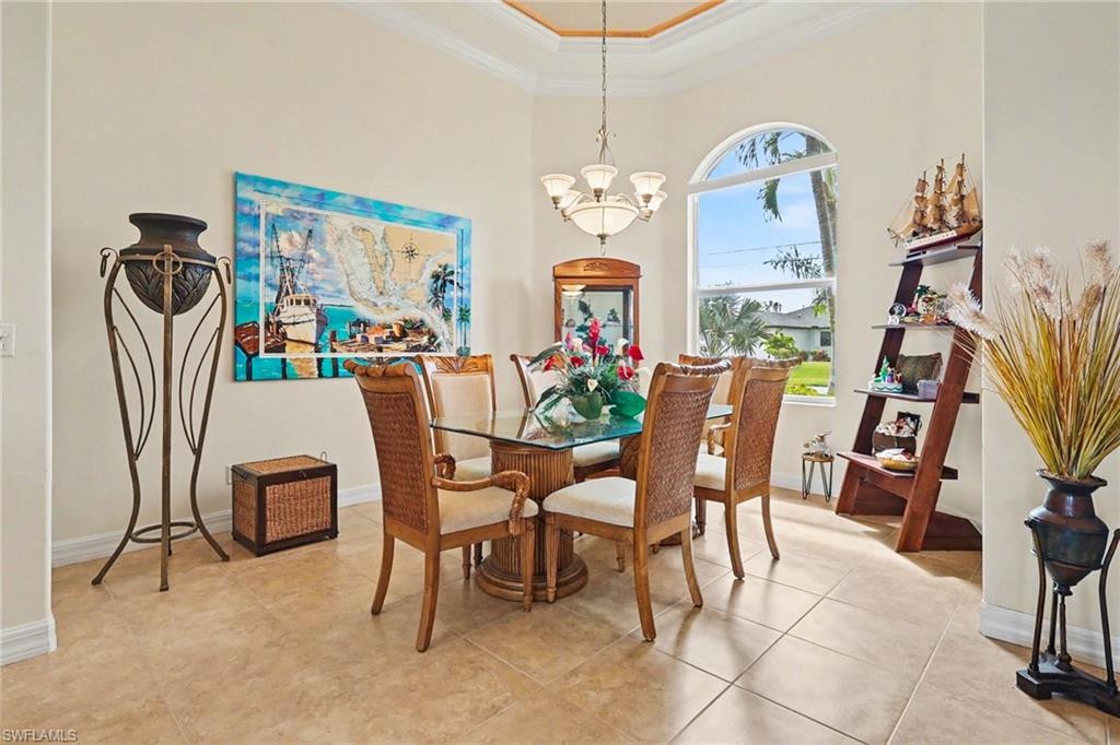 Dining room with ornamental molding, a chandelier, a high ceiling, and light tile patterned floors