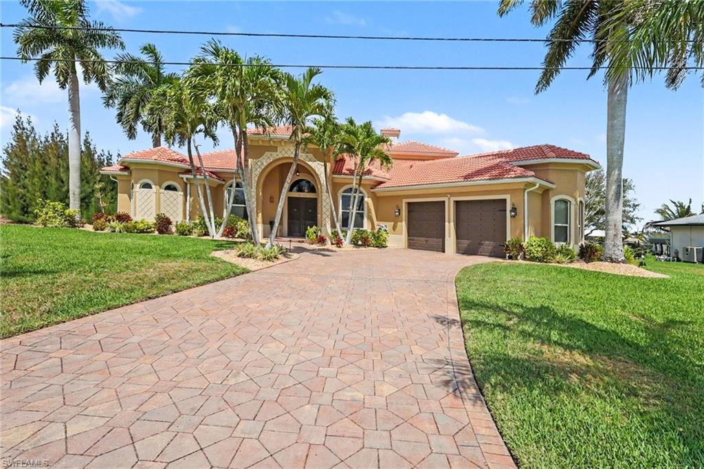Mediterranean / spanish home featuring a tile roof, decorative driveway, an attached garage, stucco siding, and a front yard