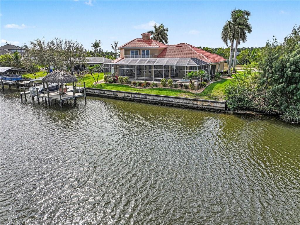 Dock area with a sunroom, boat lift, and a water view