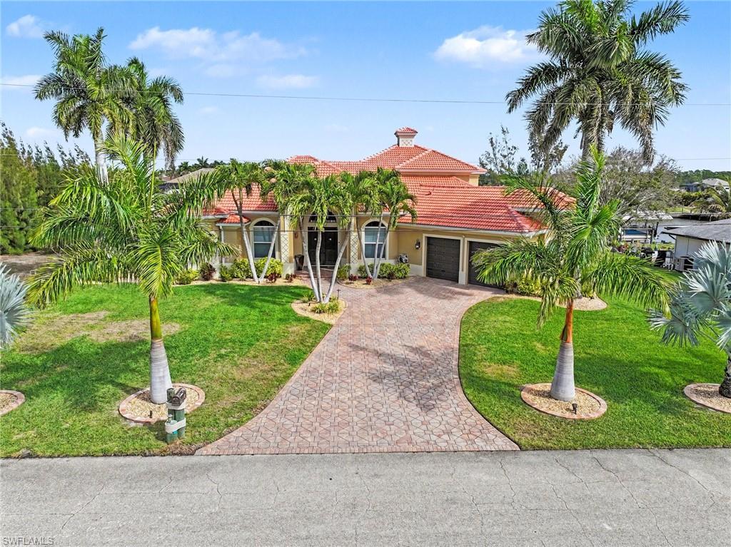 Mediterranean / spanish-style house with a yard, stucco siding, an attached garage, a tiled roof, and decorative driveway