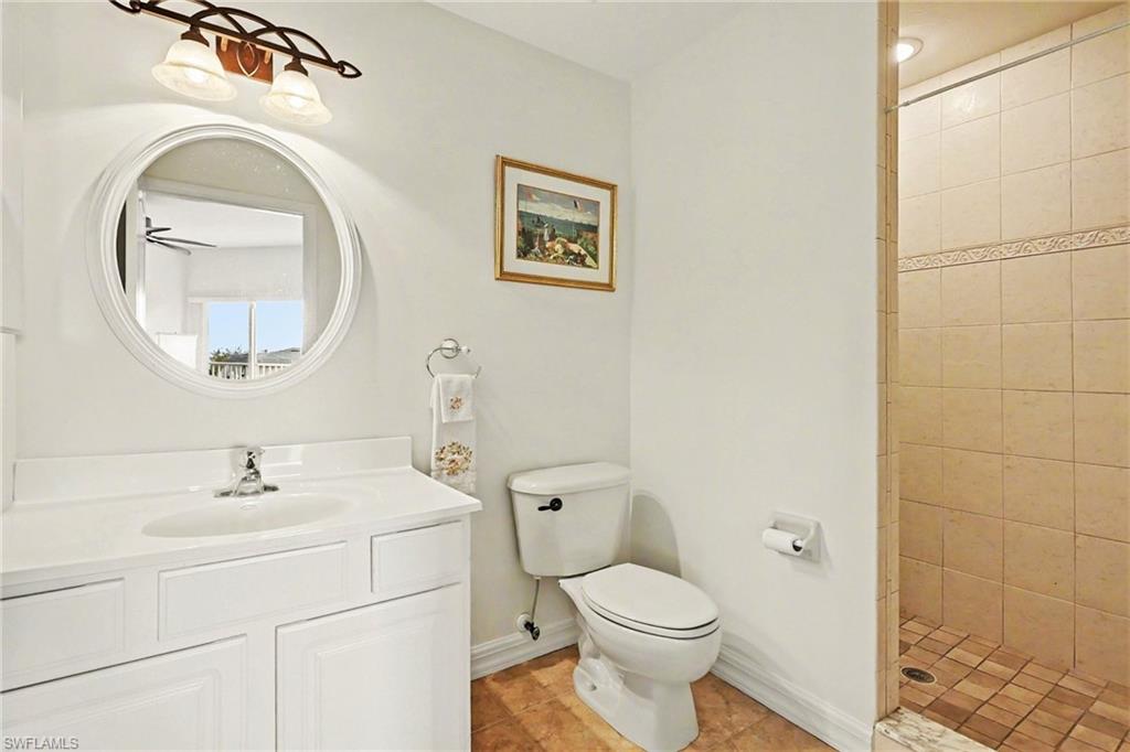 Full bath with vanity, tiled shower, and light tile patterned floors