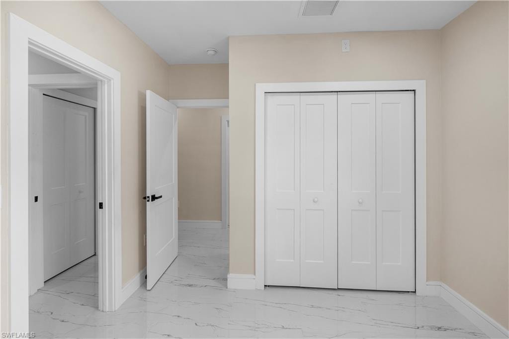 Unfurnished bedroom with a closet and light marble finish flooring