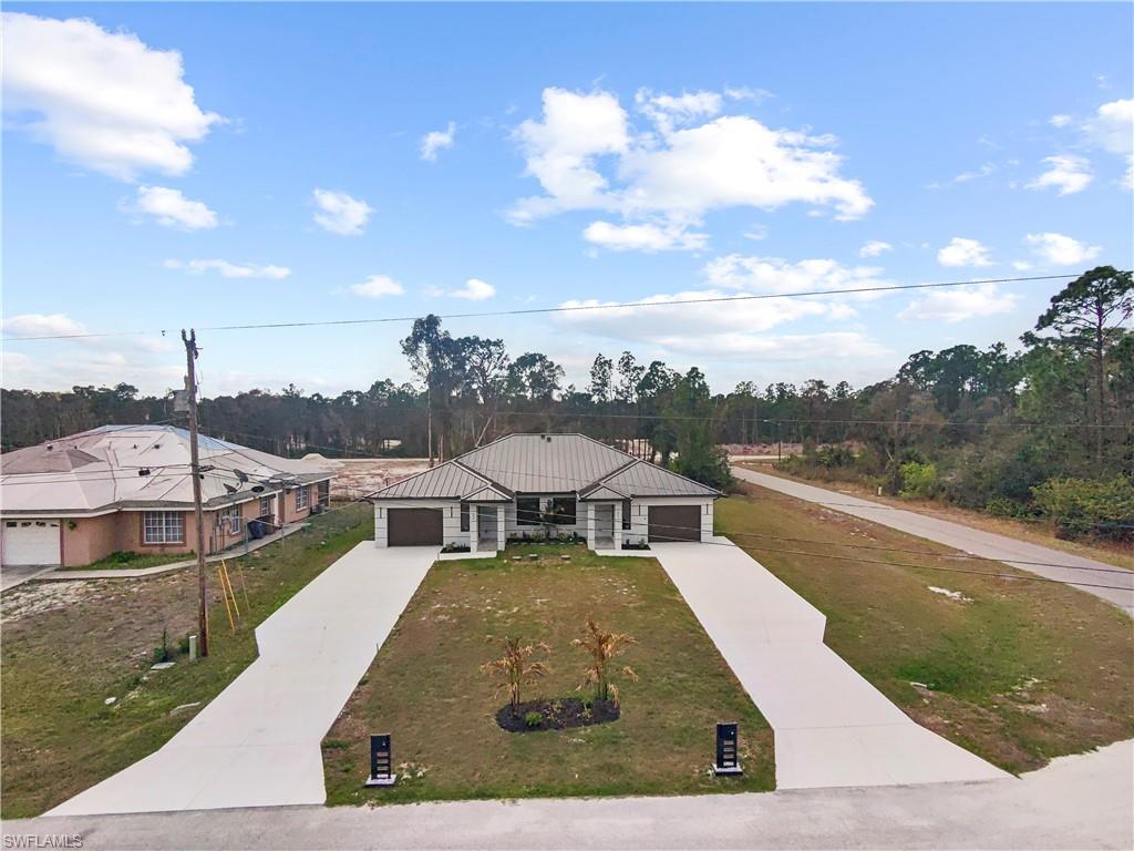 View of front of home with concrete driveway, a front lawn, a standing seam roof, and an attached garage