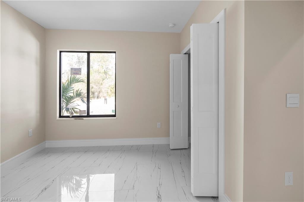 Unfurnished bedroom featuring light marble finish flooring and baseboards