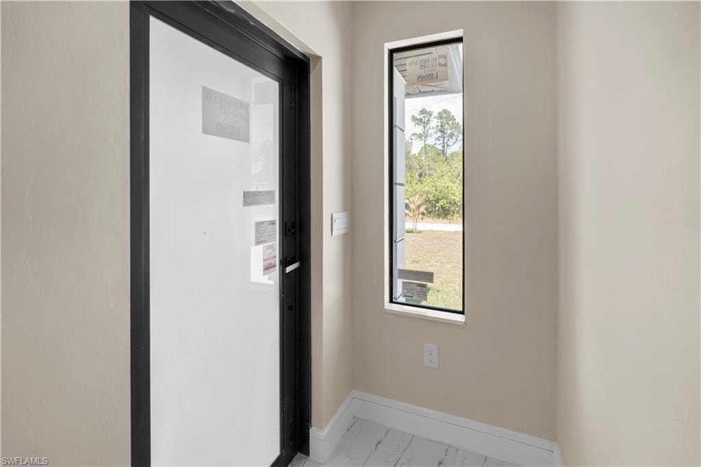 Doorway with baseboards and marble finish flooring