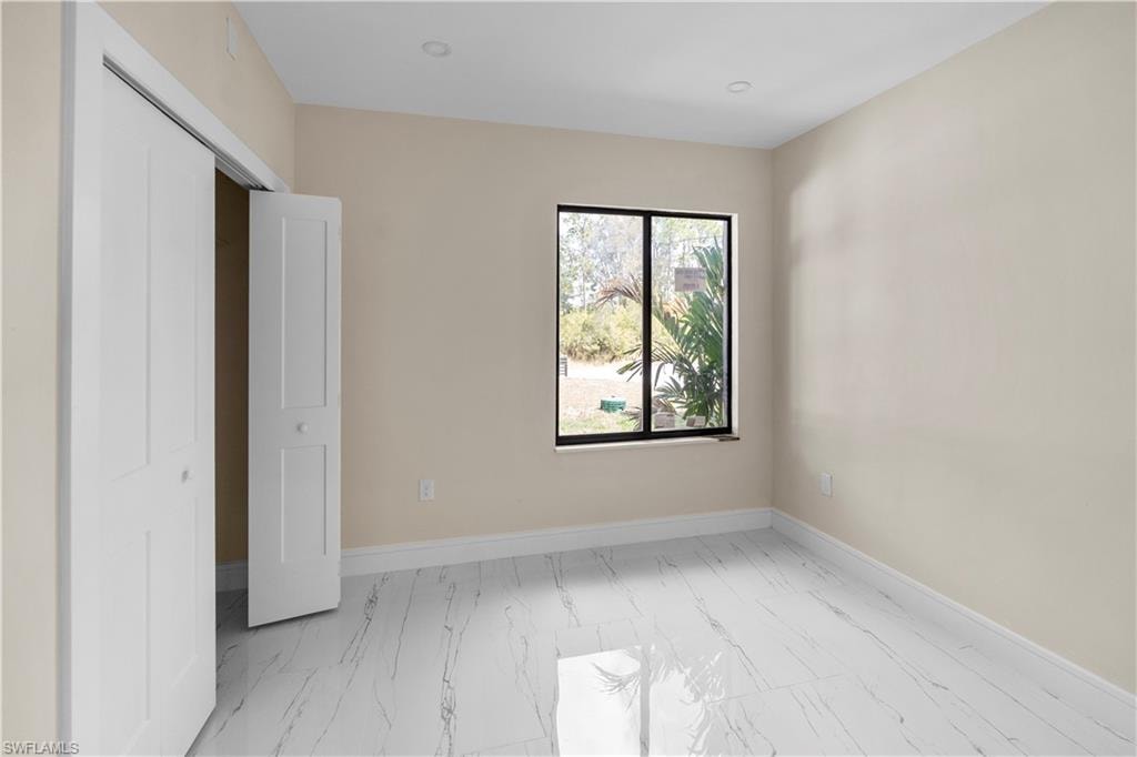 Unfurnished bedroom with light marble finish flooring and a closet