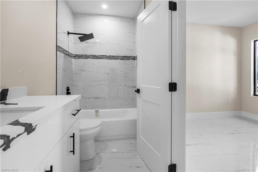 Full bathroom featuring vanity, shower / tub combination, and light marble finish flooring