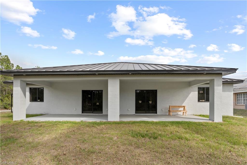 Rear view of property featuring a patio, a lawn, and stucco siding