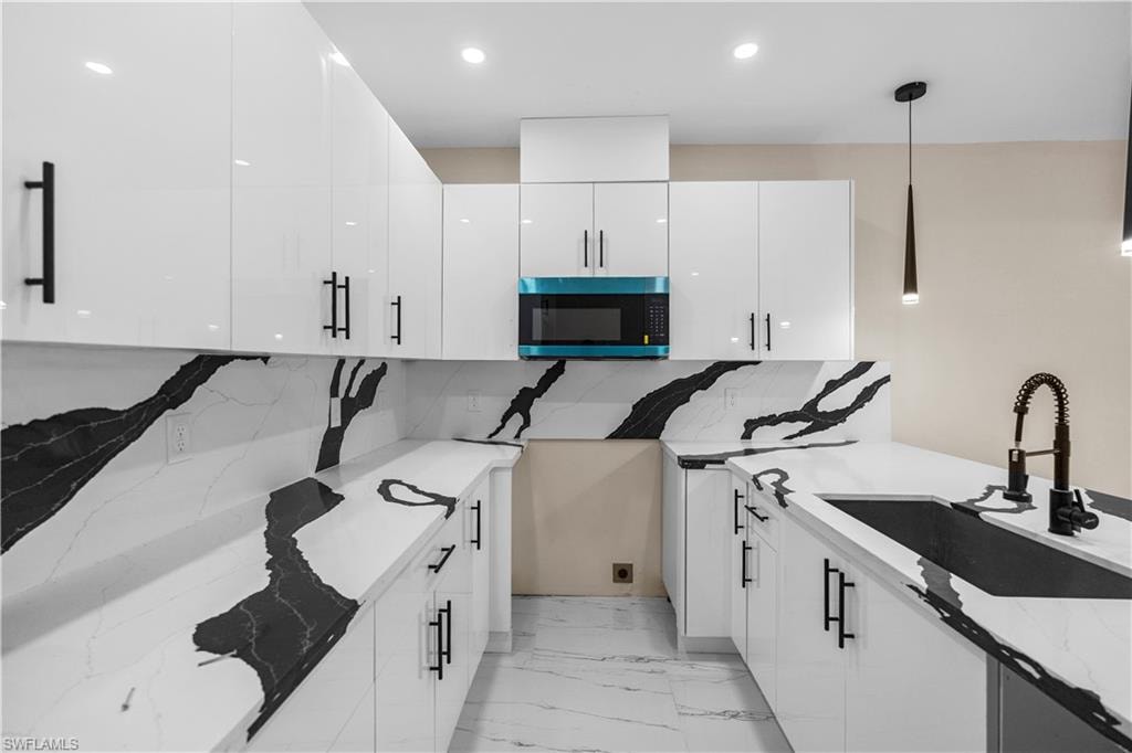Kitchen featuring white cabinetry, pendant lighting, light stone countertops, and modern cabinets