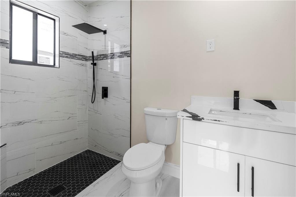Bathroom featuring vanity and a marble finish shower