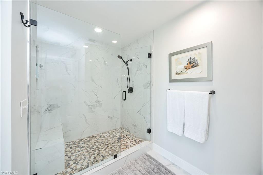 Full bathroom with a marble finish shower, recessed lighting, and light marble finish floors