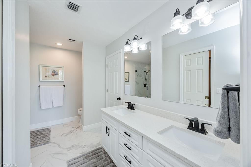 Full bathroom featuring a marble finish shower, double vanity, light marble finish floors, and recessed lighting